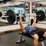 Utinon Steroids Shop: Athlet beim Bankdrücken mit hochwertigen Fitnessgeräten im modernen Gym